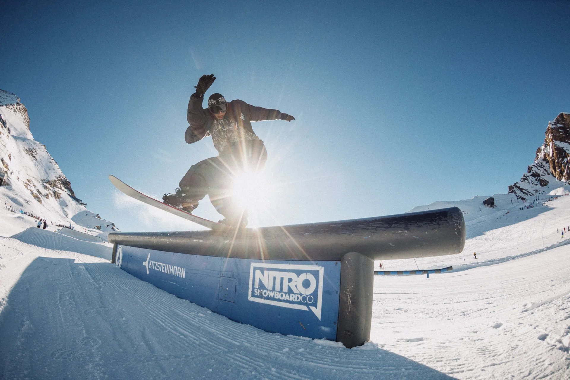 Snowboarder su un rail in controluce, con lo striscione Nitro