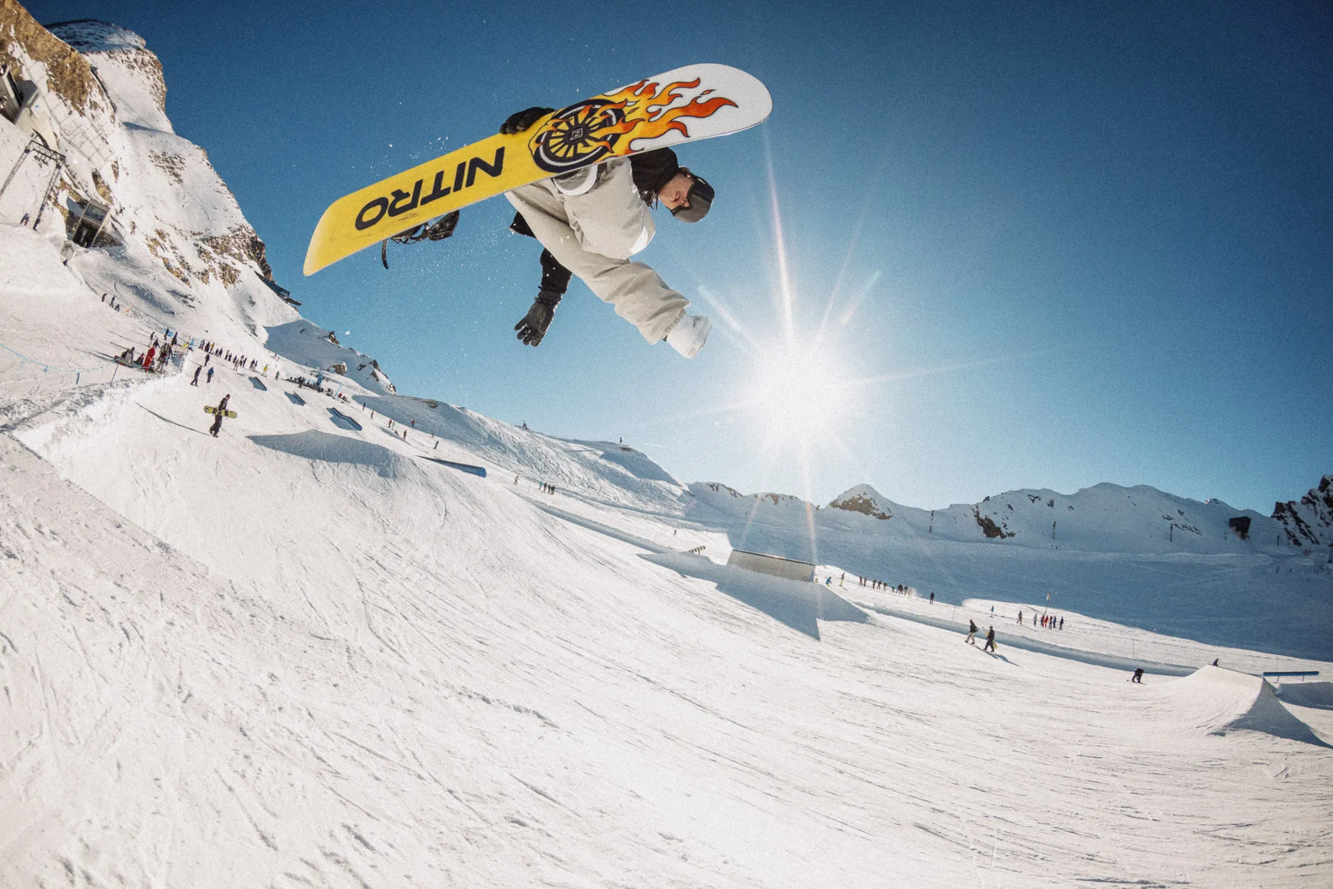 Snowboarder in volo controluce con una tavola Nitro sopra le montagne